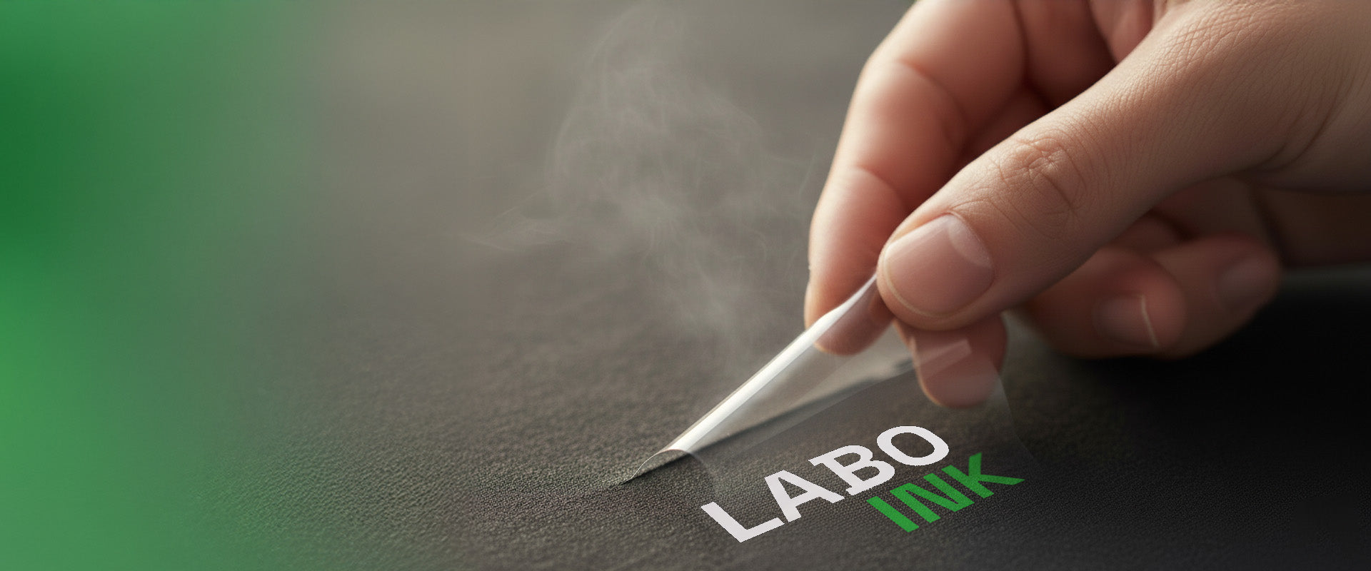 Hand peeling off 'LABO INK' on a dark textile