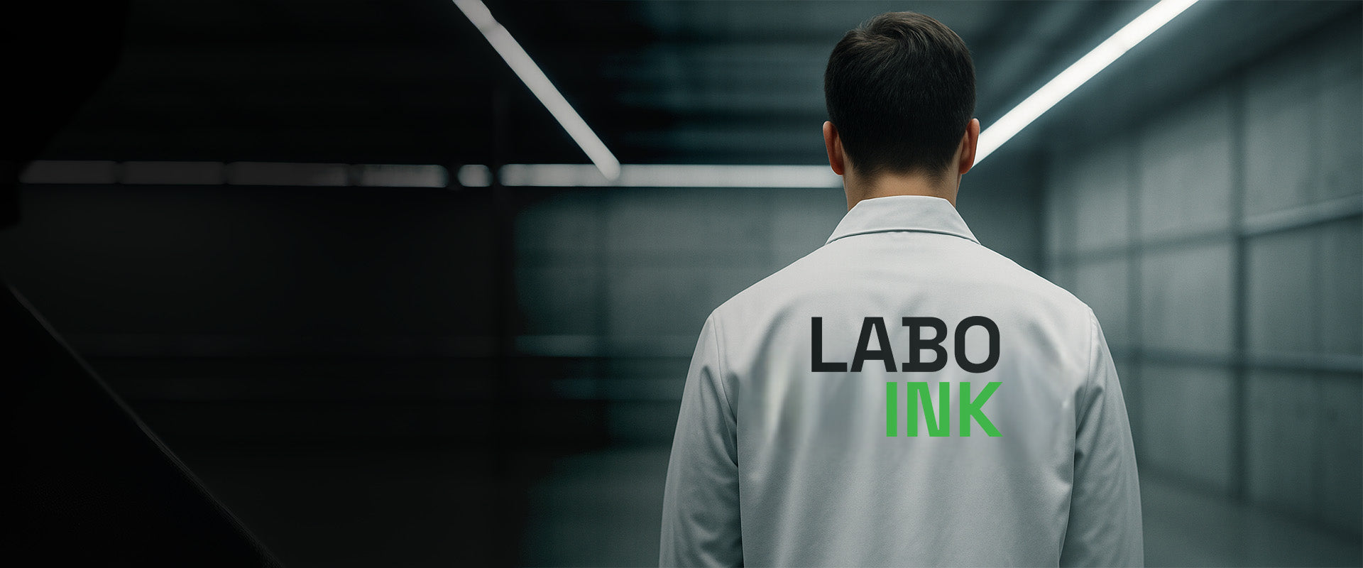 Person wearing a lab coat with 'LABO INK' on the back in a dark warehouse.