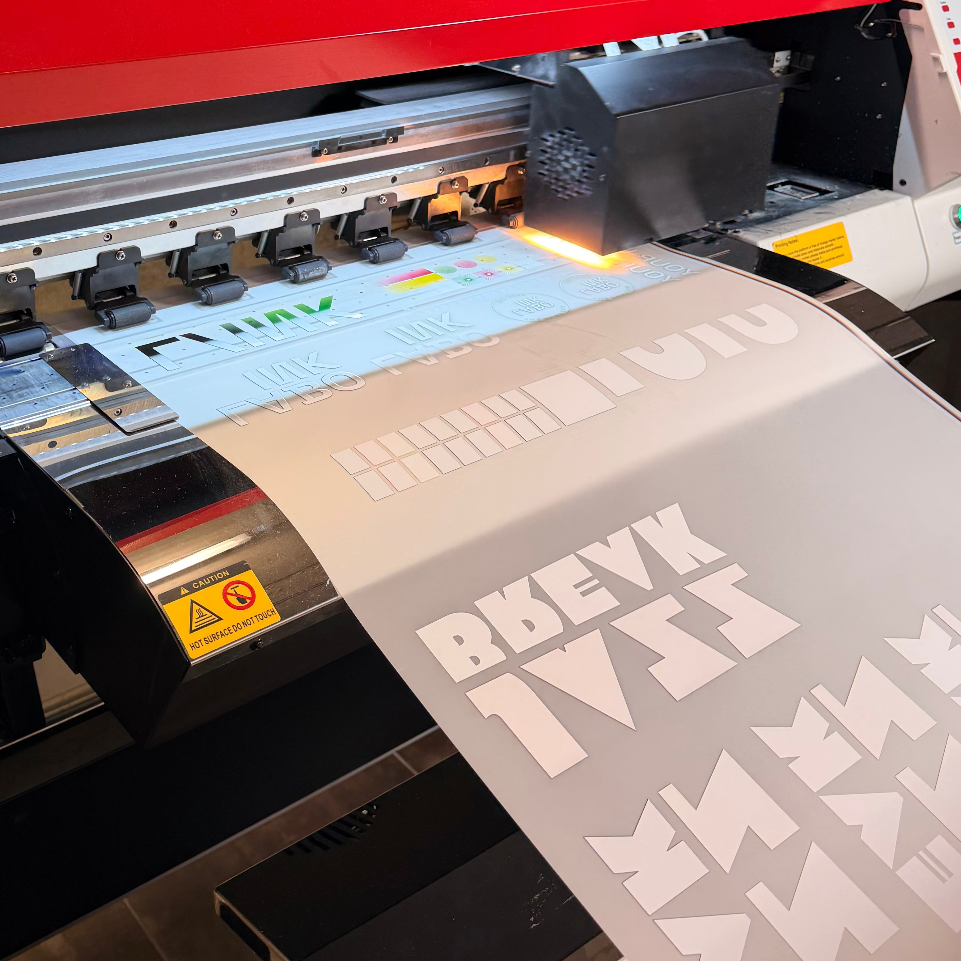 Large printing machine with a printed sheet featuring text and graphics.